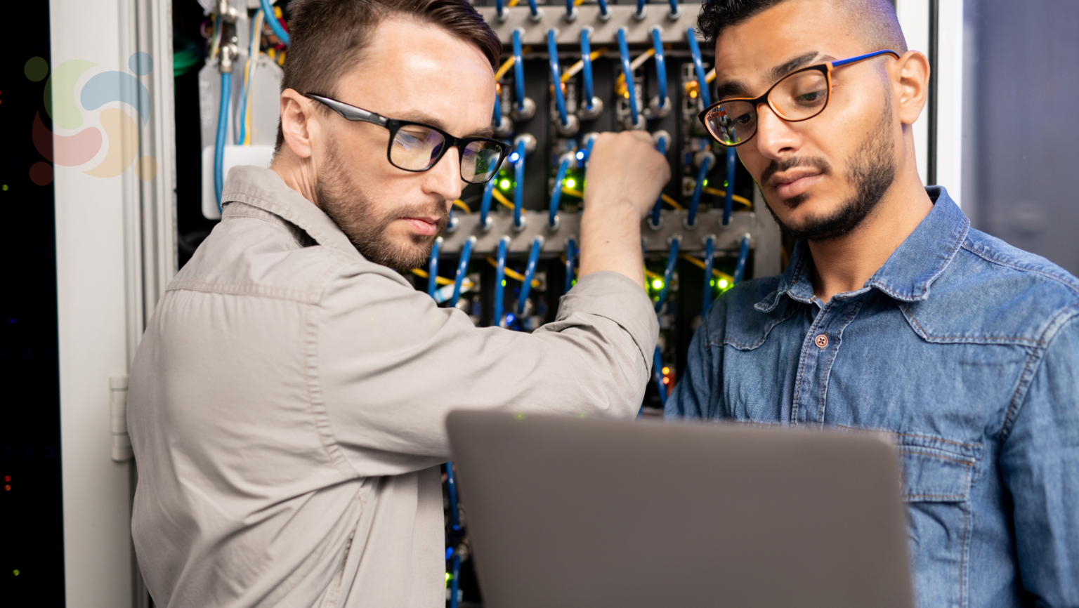 5 razões para usar Linux em servidores ao invés de Windows Server 1 Dois administradores de sistemas trabalhando em um servidor, representando o artigo sobre as '5 razões para usar Linux em servidores ao invés de Windows Server'. A imagem mostra profissionais em um ambiente técnico, com cabos e equipamentos de rede ao fundo.