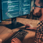 Desenvolvedor trabalhando em código de programação em dois monitores, ilustrando sincronização de processos em sistemas multiprocessados no Linux