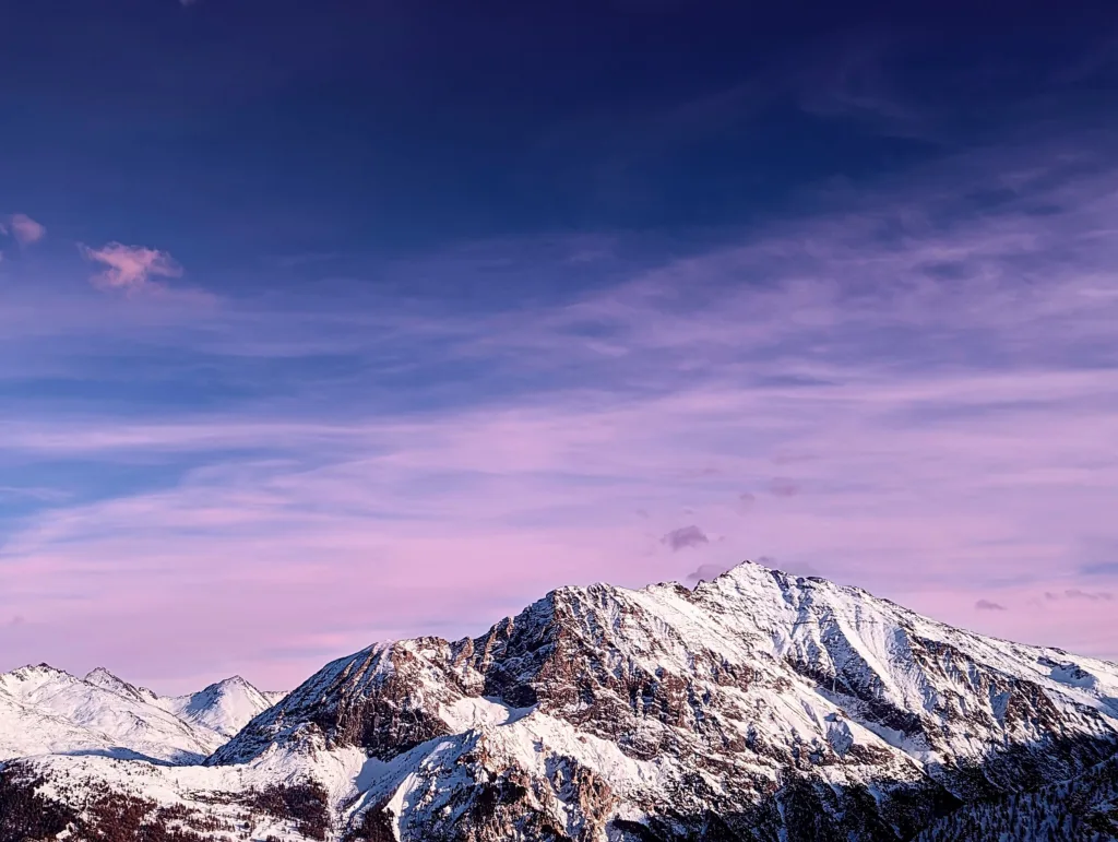 Fotografia de uma montanha nevada ao pôr do sol, com o céu em tons de rosa e azul, capturada por Gabriele Fontana.