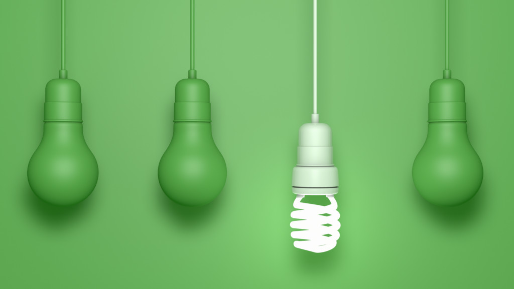 Lâmpada fluorescente branca acesa destacando-se entre três lâmpadas verdes apagadas, representando eficiência energética.