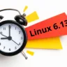 Relógio despertador marcando a hora com um papel colorido ao fundo escrito 'Linux 6.13', simbolizando a iminência do lançamento da nova versão do sistema.