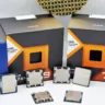 Imagem de processadores "CPUs" AMD e Intel com caixas de embalagem das linhas Ryzen 7, Ryzen 9 com tecnologia AMD 3D V-Cache e Intel Core ao fundo.