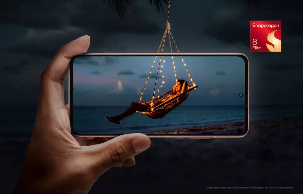 A imagem mostra uma pessoa relaxando em uma rede iluminada com luzes, pendurada em uma praia ao entardecer, vista através da tela de um smartphone. A logo "Snapdragon 8 Elite" está no canto superior direito, destacando o processador do dispositivo.