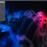 Captura de tela do desktop PorteuX 1.7 com menu de aplicativos aberto, apresentando ícones de diferentes categorias como Acessórios, Internet, Som e Vídeo, em frente a um fundo com padrões de fumaça colorida em azul e rosa.