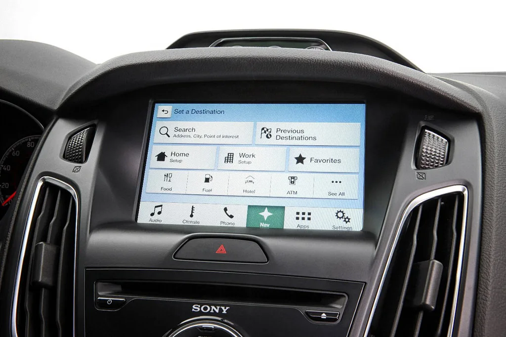 Interface de sistema de navegação automotivo com sistema operacional QNX, mostrando opções de busca de destino, favoritos e configurações de áudio e clima.