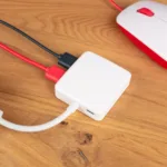 Hub USB 3.0 da Raspberry Pi conectado a um mini-PC Raspberry Pi e periféricos, incluindo mouse, em uma mesa de madeira. Ideal para expandir a conectividade de dispositivos.