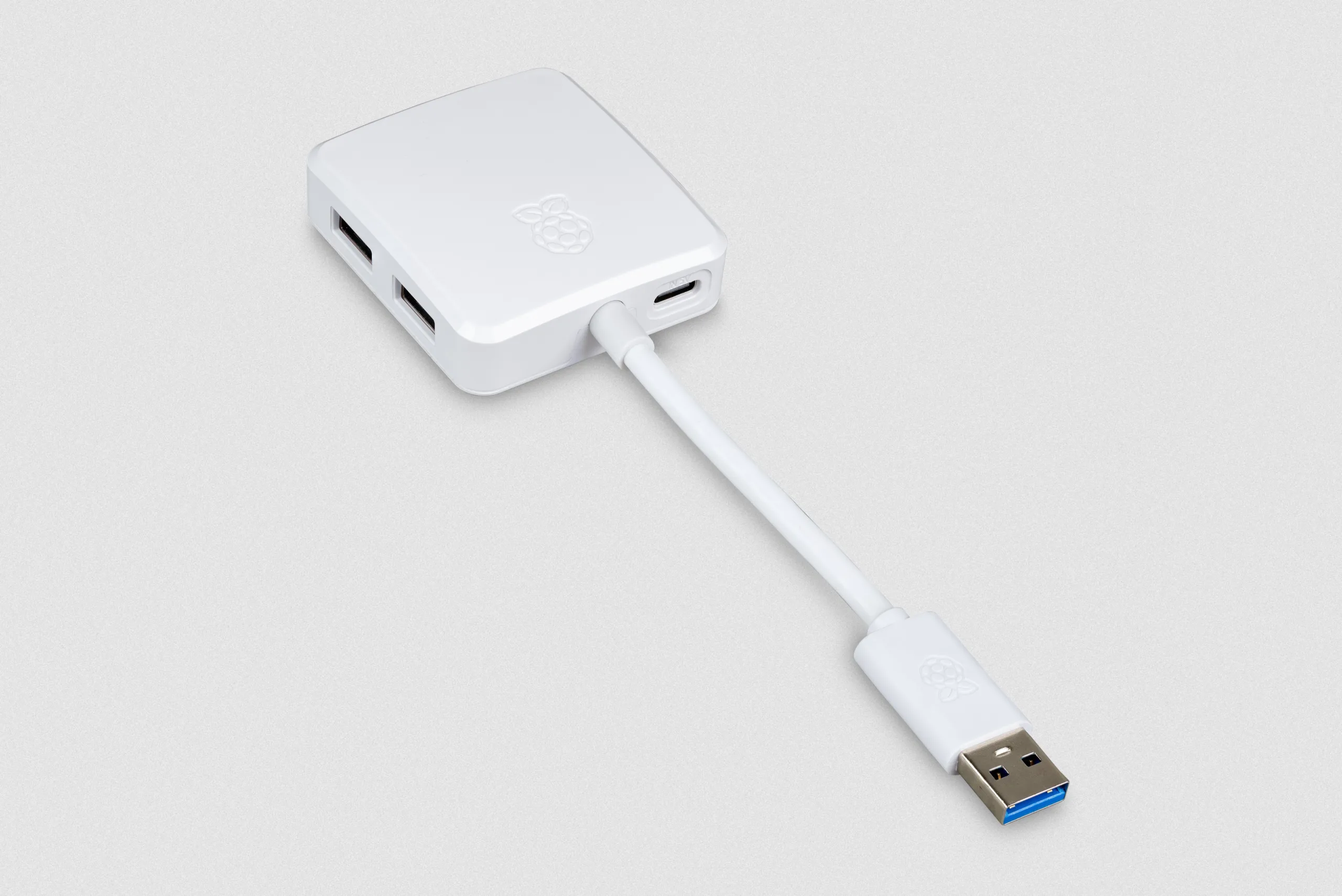 Novo hub USB 3 para Raspberry Pi chega ao mercado por apenas $12 2 Hub USB 3.0 oficial da Raspberry Pi com design compacto em branco, contendo um cabo fixo USB-A de 8 cm e quatro portas USB para expansão de conexões.