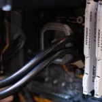 Close-up de módulos de memória RAM DDR4 HyperX instalados em um computador, com detalhes do sistema de refrigeração líquida e componentes internos, representando tecnologia de hardware de alto desempenho.