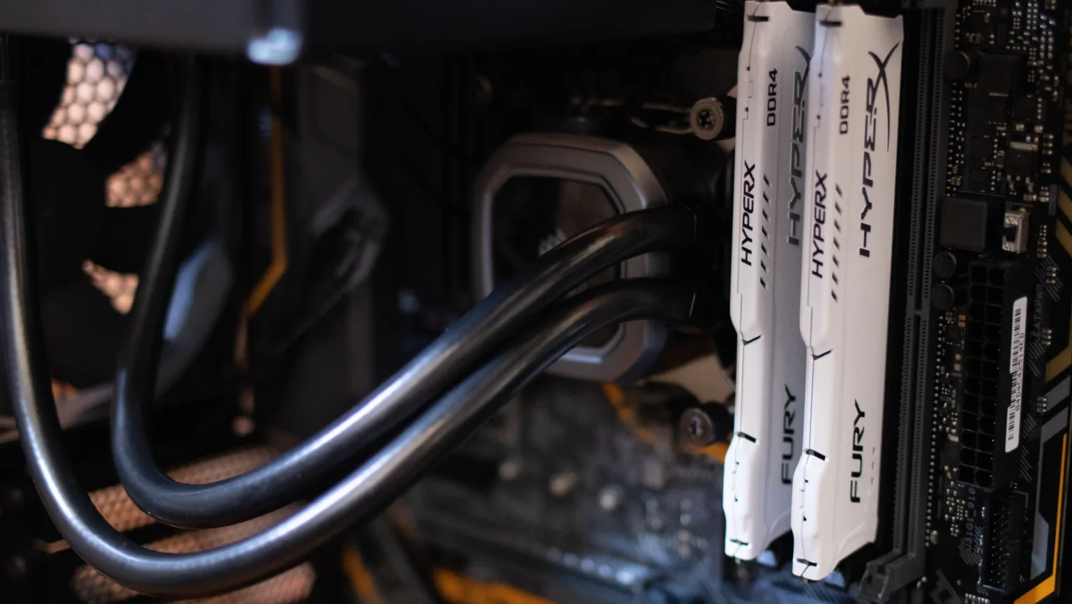 DMA P2P: a tecnologia que está revolucionando a troca de dados entre dispositivos 1 Close-up de módulos de memória RAM DDR4 HyperX instalados em um computador, com detalhes do sistema de refrigeração líquida e componentes internos, representando tecnologia de hardware de alto desempenho.