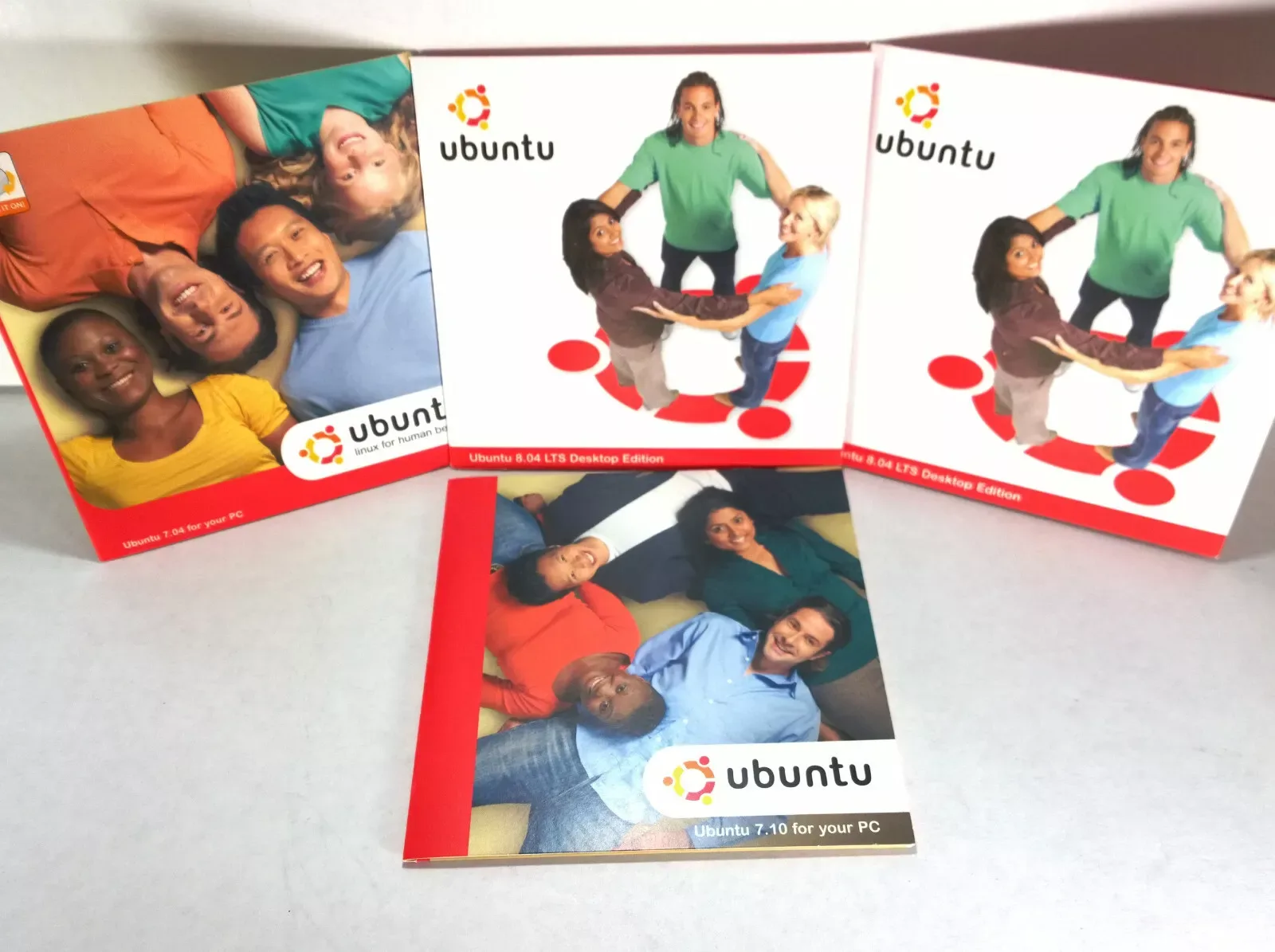 Kits ShipIt com capas de Ubuntu 7.04, 7.10 e 8.04 ilustram a história do bug do CD de graça Ubuntu