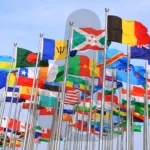 Diversas bandeiras de países com a silhueta do mascote Linux ao fundo, representando as restrições Linux internacional e batalhas legais Linux ao redor do mundo.