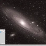Captura de tela do HeliumOS 10 exibindo o ambiente KDE Plasma com painel inferior e menu de aplicativos aberto sobre papel de parede da galáxia Andrômeda.