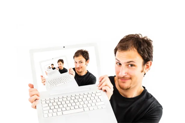 Homem segurando laptop branco com a tela mostrando recursivamente a mesma imagem, representando a janela infinita no terminal Linux com múltiplas instâncias em sequência