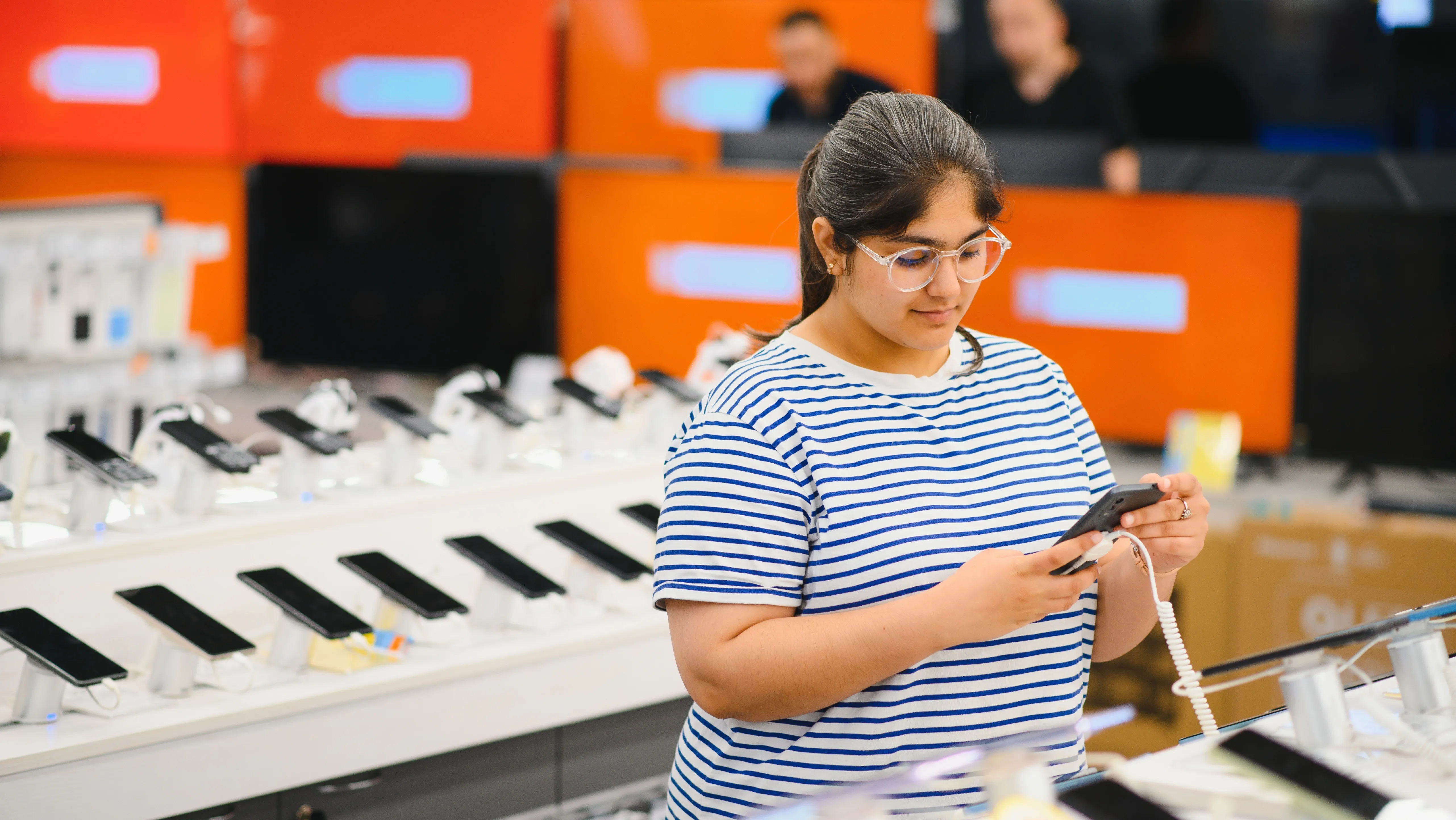 Pessoa segurando smartphone e comparando suporte de software, assistência técnica e valor de revenda do aparelho