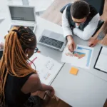 linda elegante equipe sentado no escritorio mesa usando um laptop e ouvir um colega