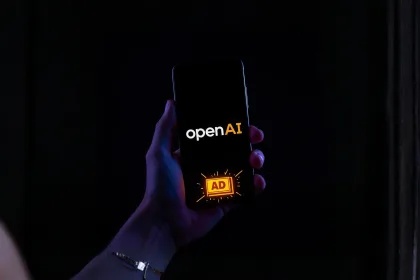 Mão segurando um smartphone em modo escuro com o logo da OpenAI e um selo “AD” em amarelo na tela