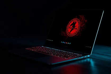 Notebook em mesa escura, com teclado iluminado em vermelho e o logotipo do FreeBSD na tela em modo escuro.