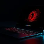 Notebook em mesa escura, com teclado iluminado em vermelho e o logotipo do FreeBSD na tela em modo escuro.